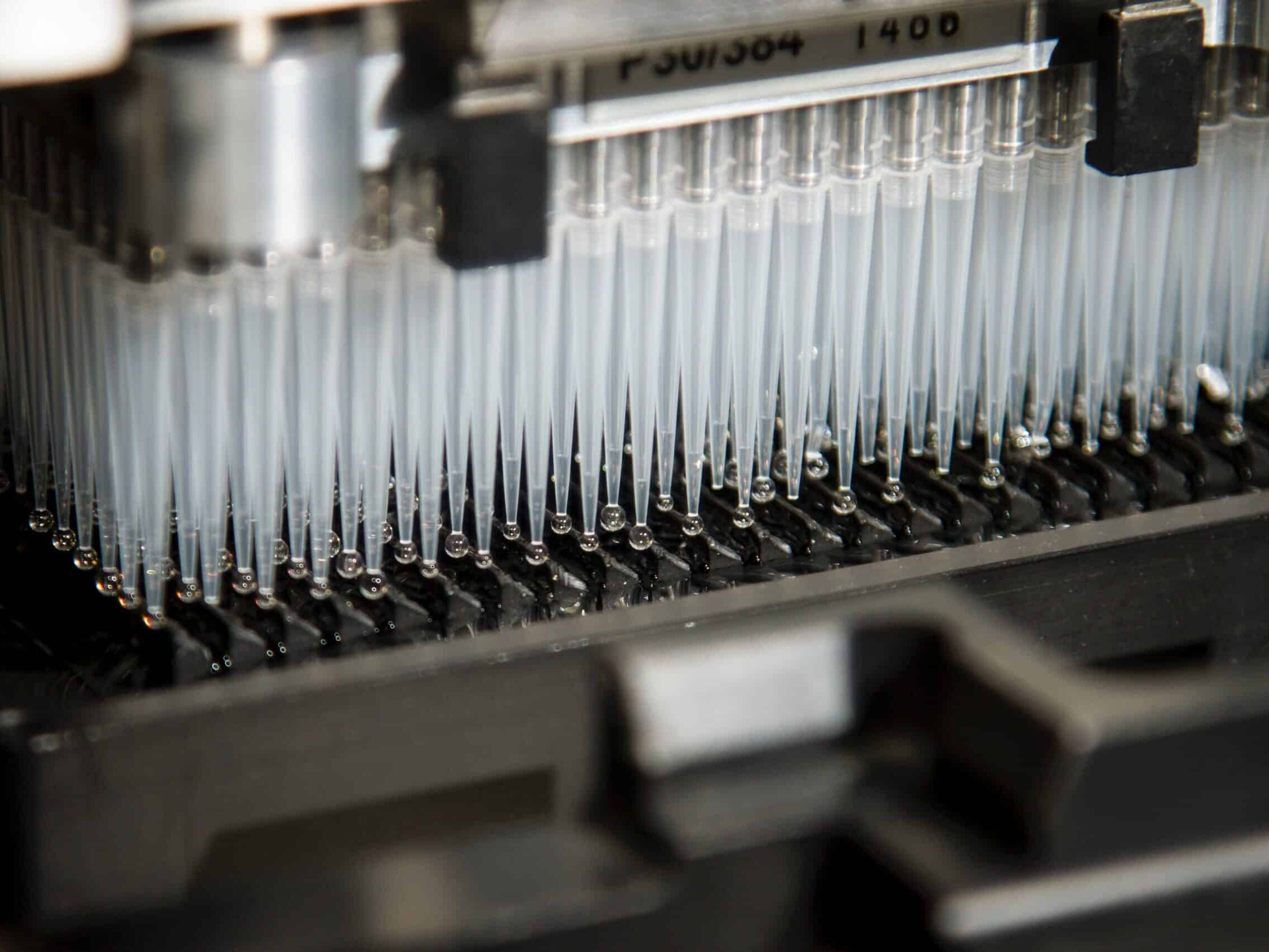 Photo of a gray lab machine with pipettes by National Cancer Institute on Unsplash.