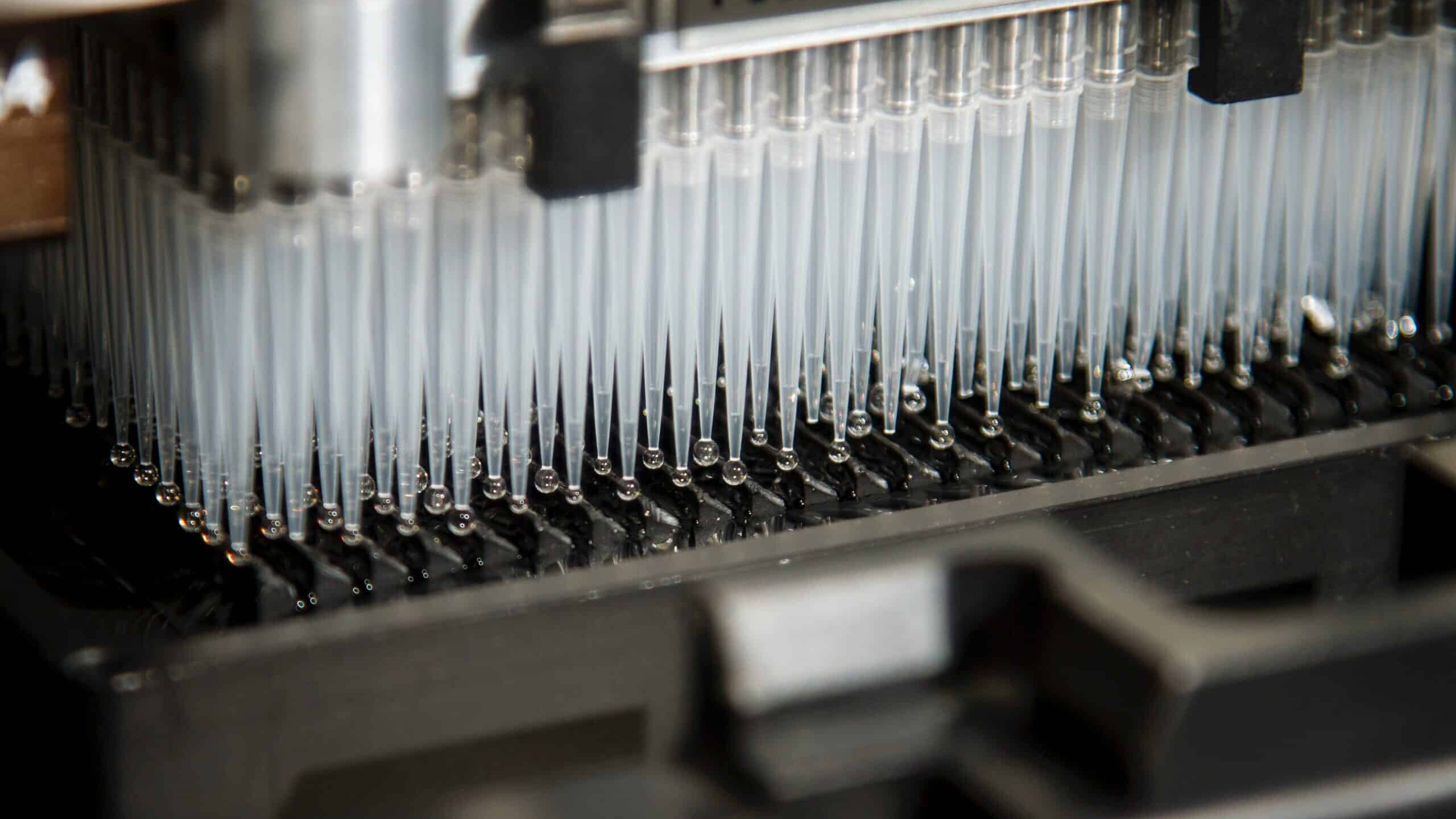 Photo of a gray lab machine with pipettes by National Cancer Institute on Unsplash.