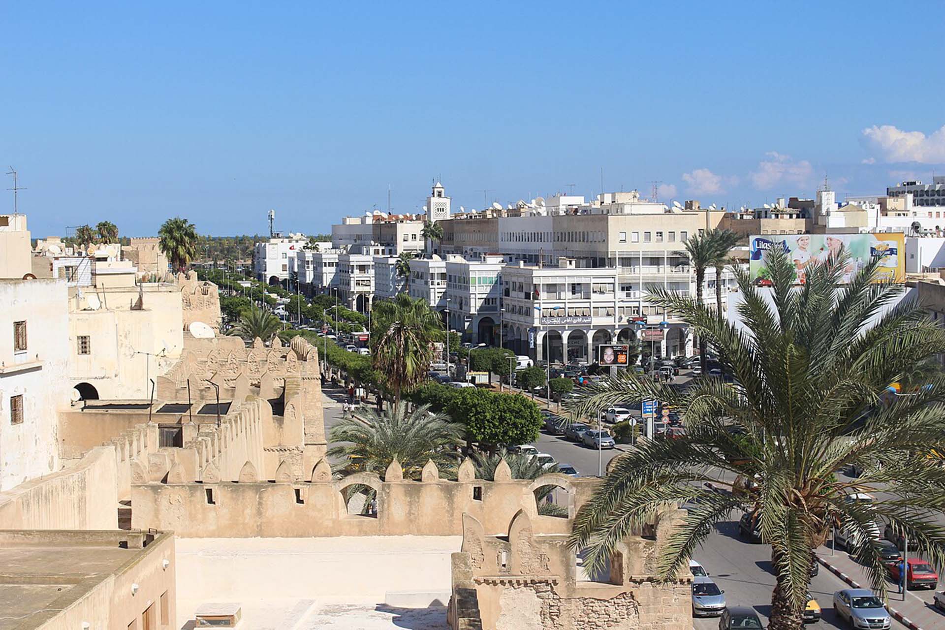 Dies ist ein Panoramablick von einem Aussichtsturm auf die Kasbah von Sfax. Von diesem Panoramablick aus kann man die Stadtmauer von Sfax, die Avenue Ali Balhaouane und die Gebäude mit Blick auf die Avenue Ali Balhaouane sehen. Urhebender: Csisc (https://commons.wikimedia.org/wiki/File:Murailles_de_sfax_vue_casbah_sfax_avenue_ali_balhaouane.jpg), „Murailles de sfax vue casbah sfax avenue ali balhaouane“, https://creativecommons.org/licenses/by-sa/4.0/legalcode