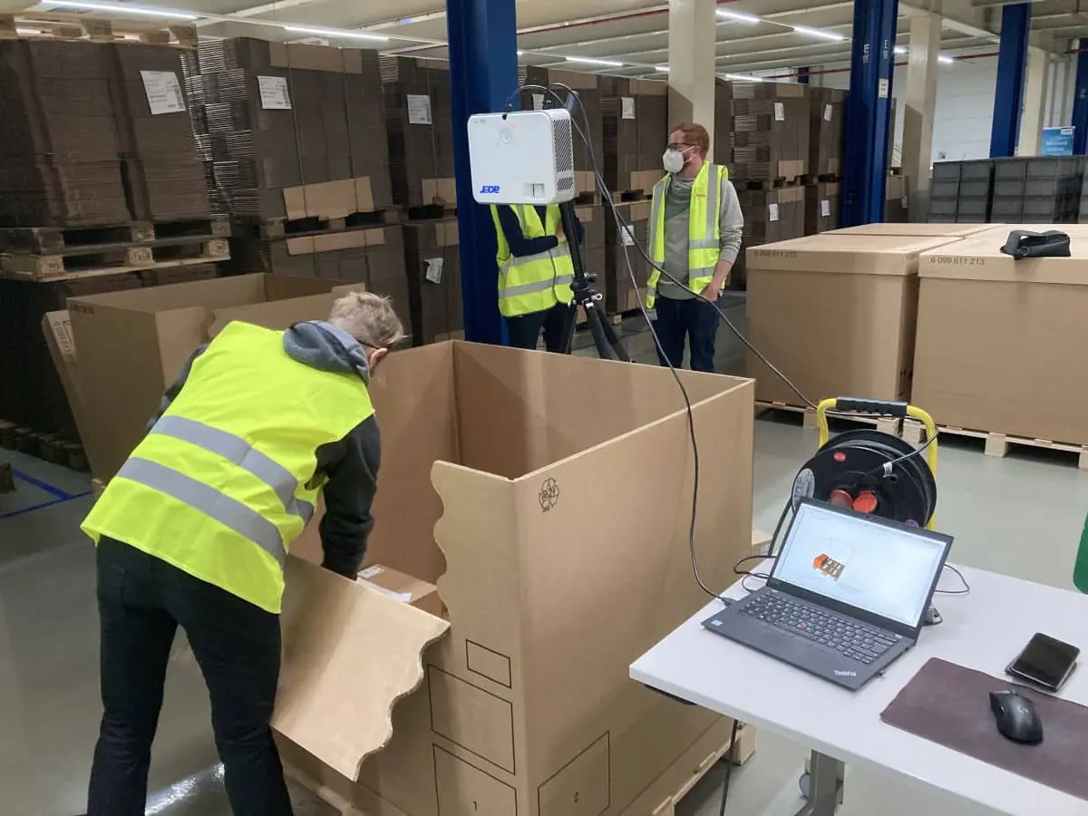 A beamer positioned over a large shipping crate for AI assisted packing in a warehouse