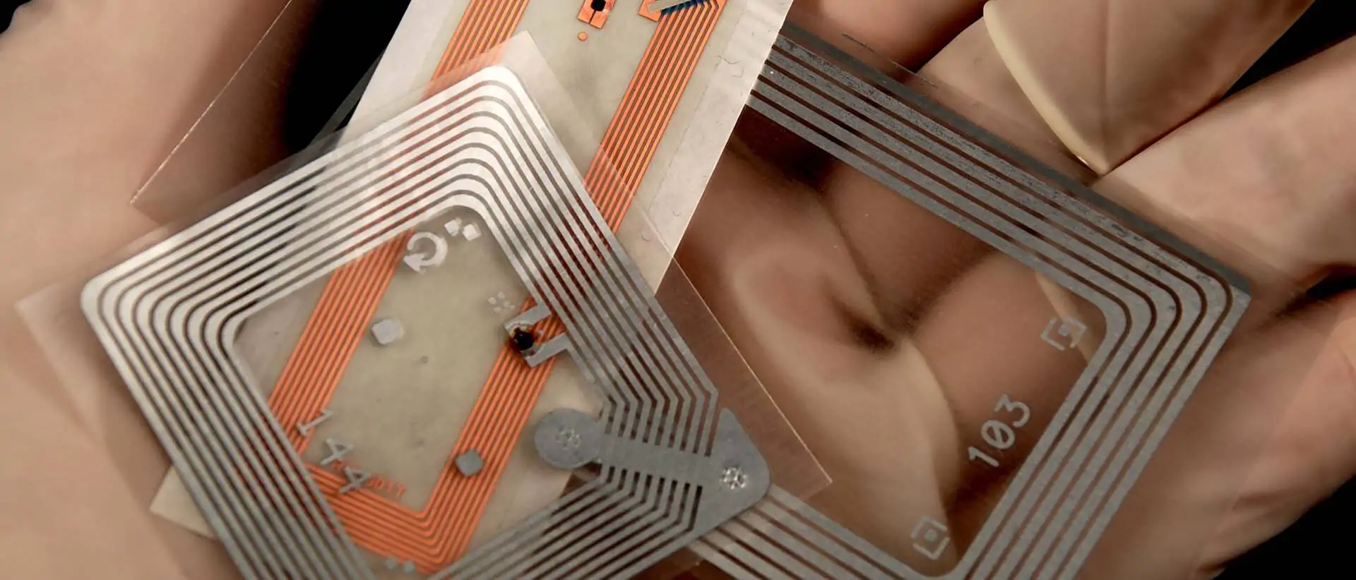 RFID-Chips auf einer mit Gummhandschuhen geschützten Hand - Titelbild RFID-Beitrag