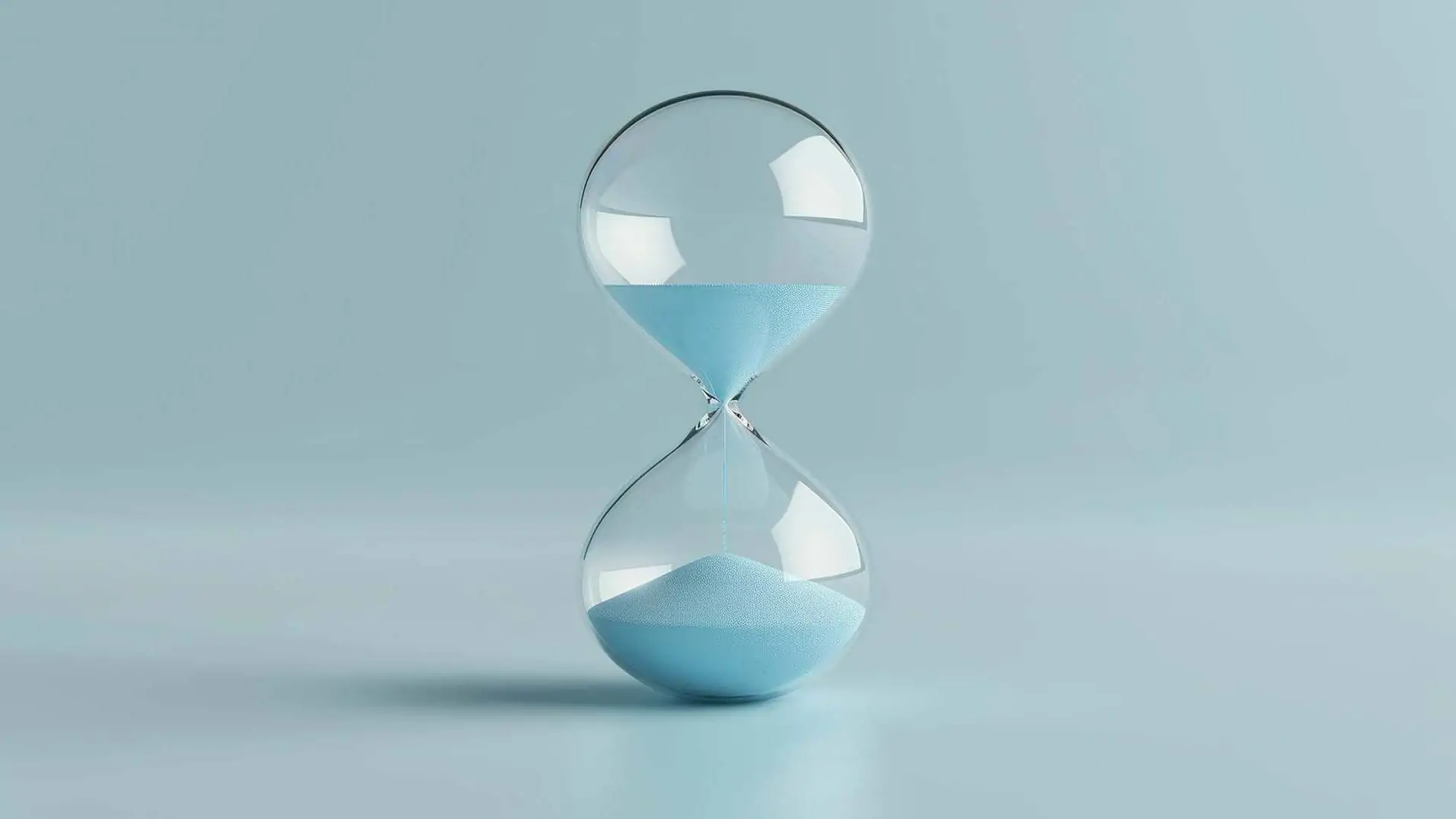 Sanduhr mit blauem Sand auf einem weichen blauen Hintergrund, die den Lauf der Zeit und die flüchtigen Momente des Lebens symbolisiert und die Bedeutung von Zeitmanagement und Reflexion betont
