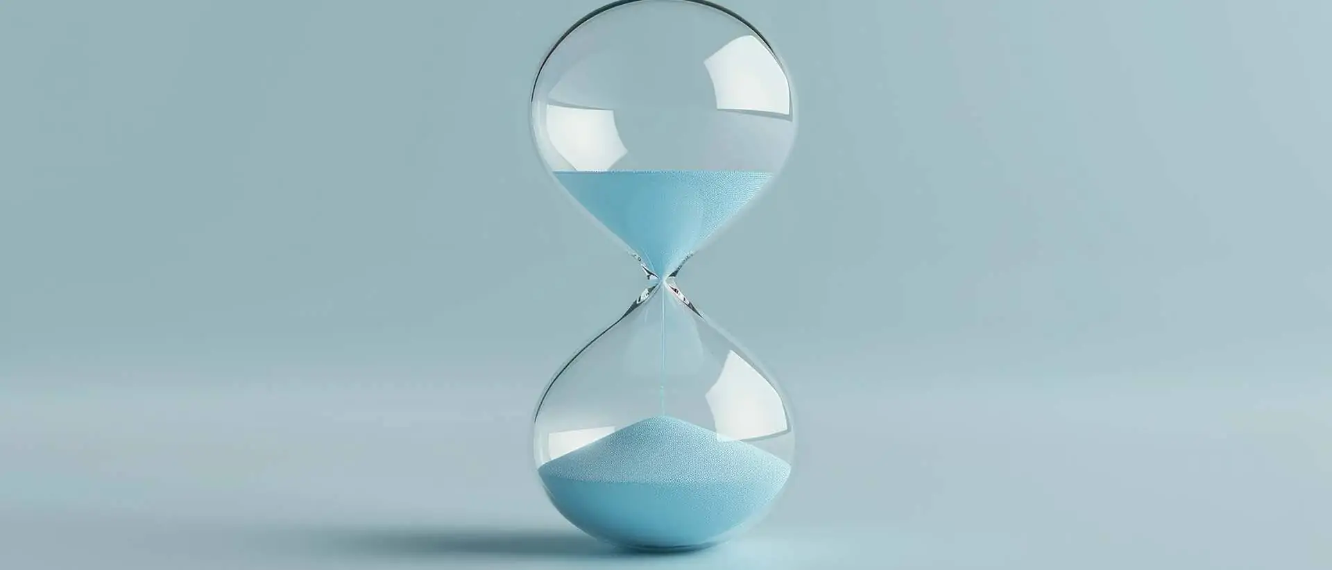Sanduhr mit blauem Sand auf einem weichen blauen Hintergrund, die den Lauf der Zeit und die flüchtigen Momente des Lebens symbolisiert und die Bedeutung von Zeitmanagement und Reflexion betont