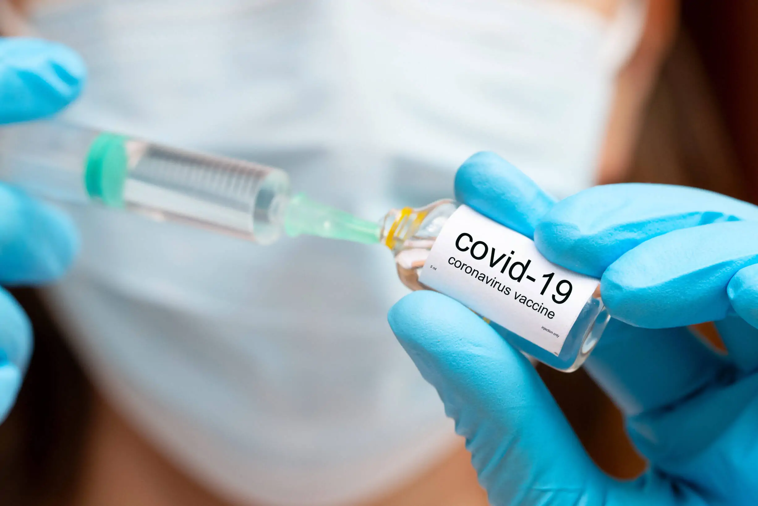 covid vaccine injection, hands in medical gloves with vaccine ampoula and syringe