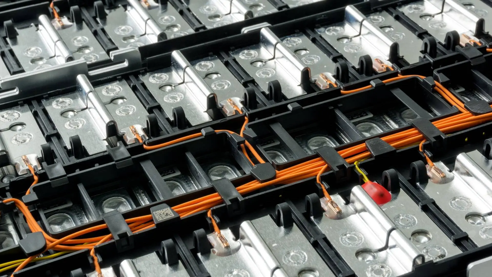 Aus der Batteriefertigung: Selektiver Fokus auf den Lithium-Akku eines Elektroautos und die internen Kabelverbindungen zwischen den Zellen vor einem Hintergrund.