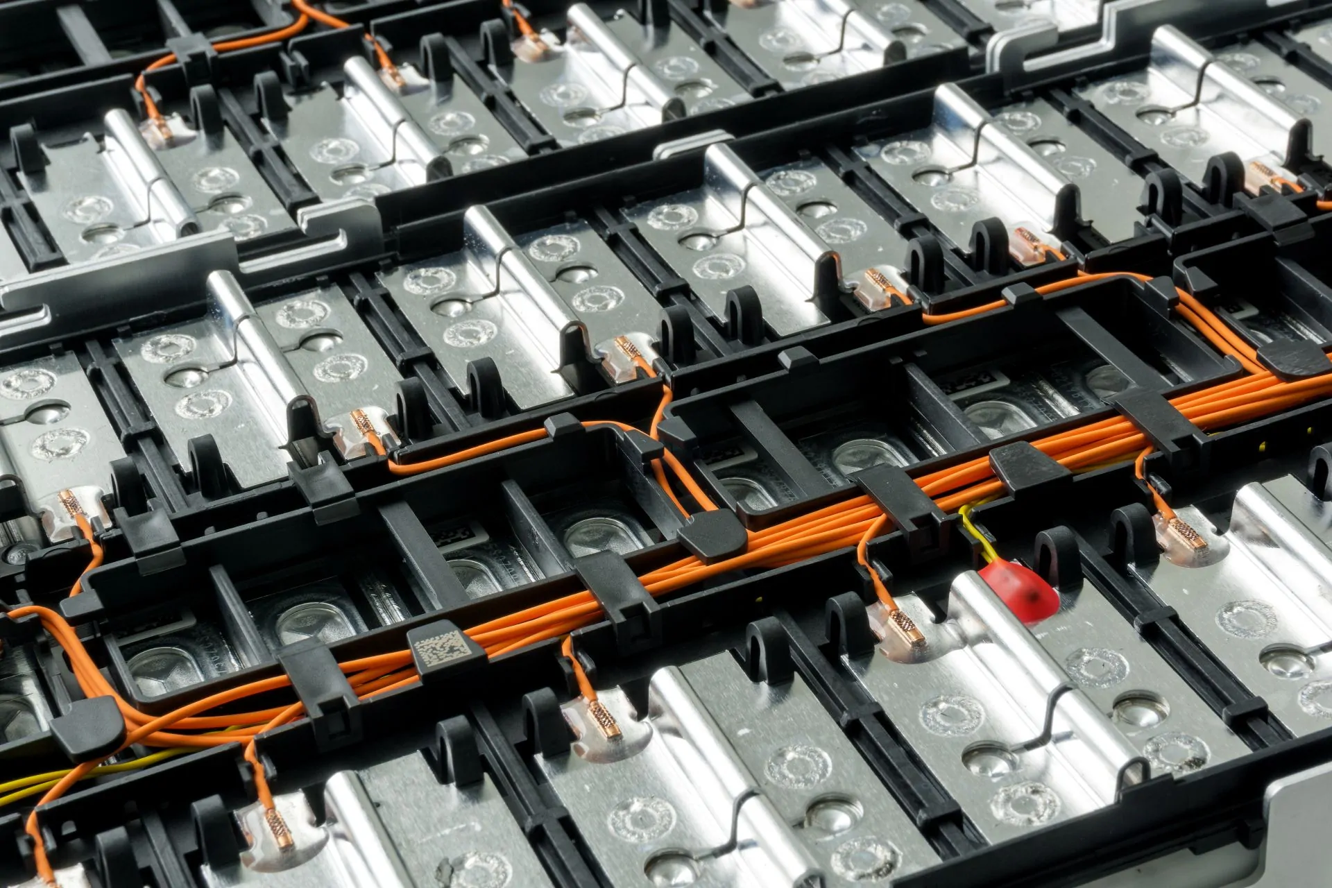 Aus der Batteriefertigung: Selektiver Fokus auf den Lithium-Akku eines Elektroautos und die internen Kabelverbindungen zwischen den Zellen vor einem Hintergrund.